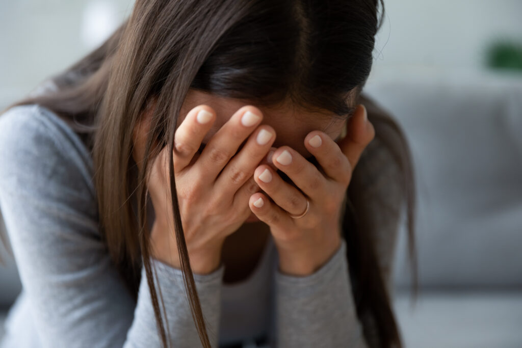 Grieving woman covering her face with hands, mourning the loss of a loved one. A wrongful death lawyer can help families seek justice and compensation after a tragic loss.